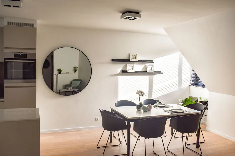 Coin repas avec des murs clairs, un store vénitien noir et un plafonnier dans l’appartement Duinenwater.